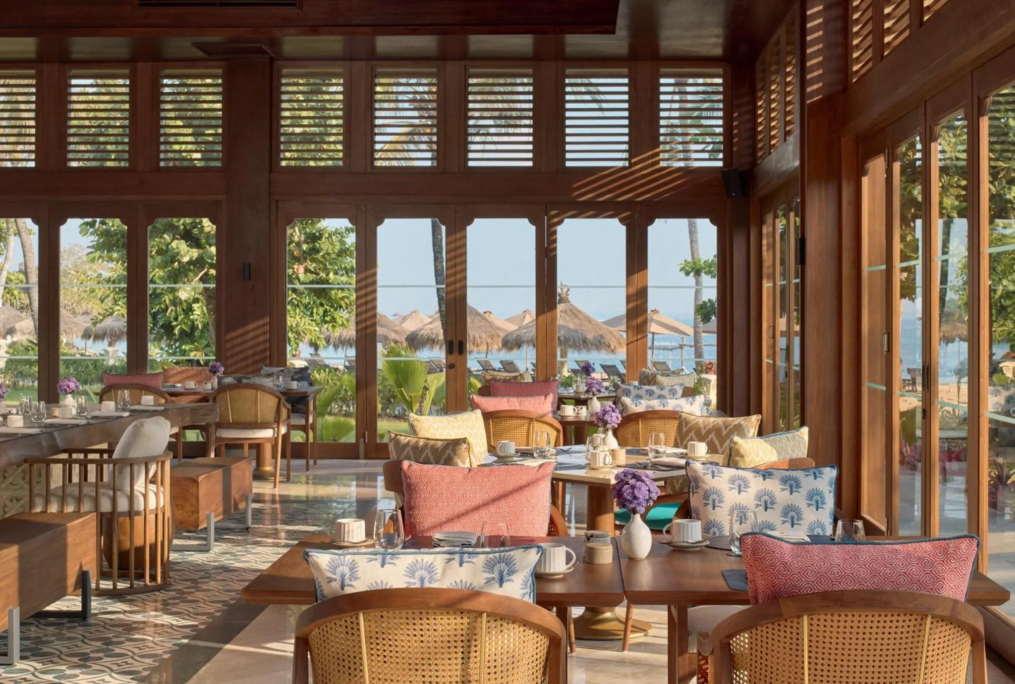 Une salle lumineuse avec des tables dressées face à une vue sur la mer.