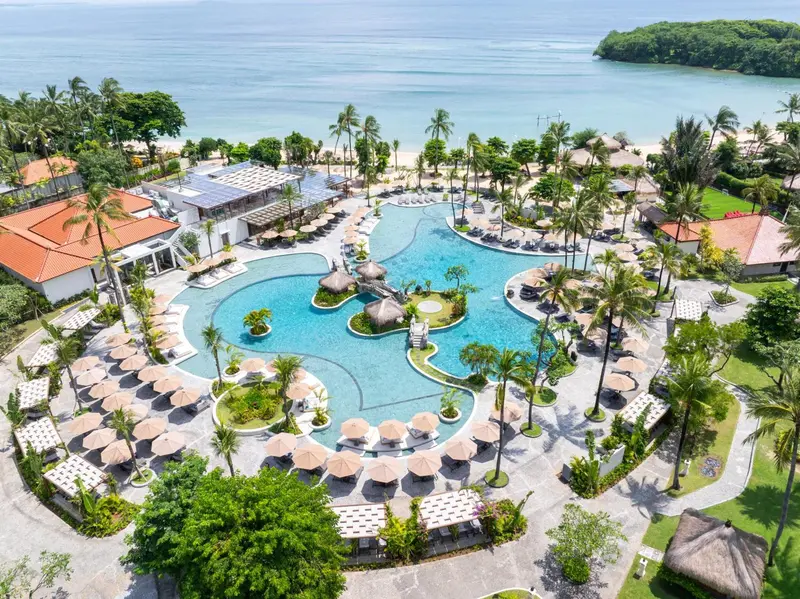 Vue aérienne d'un complexe hôtelier avec une grande piscine et une plage.