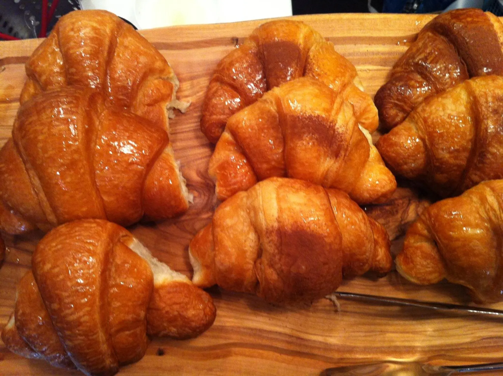 Des viennoiseries dorées sont présentées sur une planche en bois.
