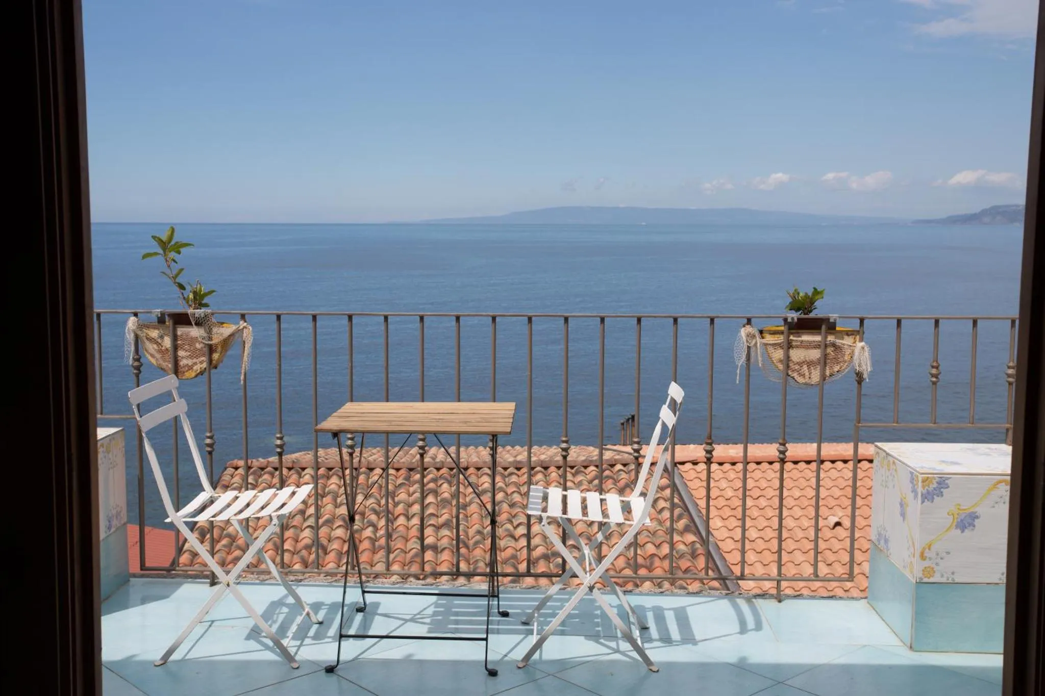 Terrasse avec mobilier en fer forgé donnant sur la mer.