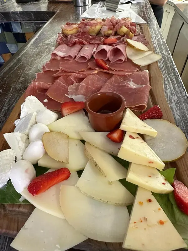 Assortiment de charcuteries et de fromages présentés sur une planche en bois.