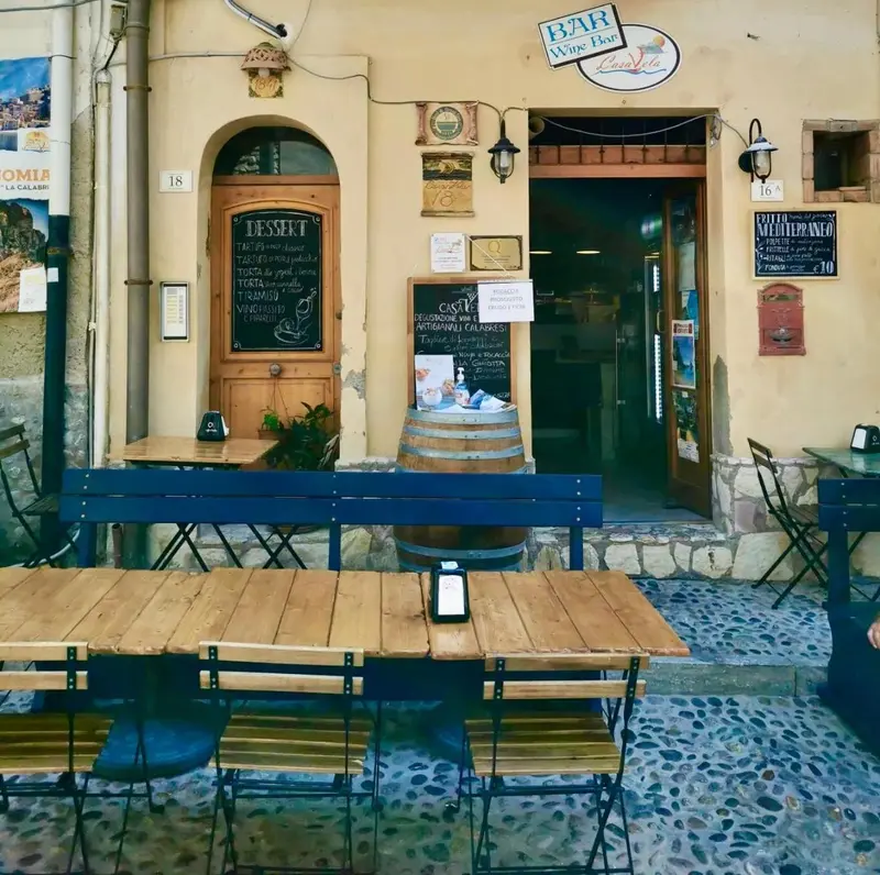Façade d'un bar avec tables en terrasse et menu à la craie.