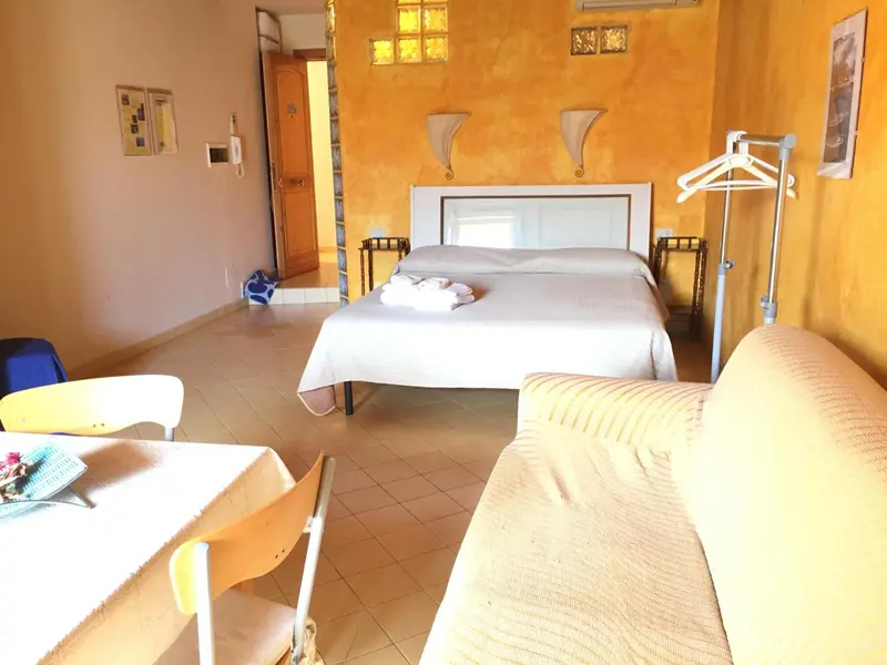 Une chambre lumineuse avec un lit double et un coin salon.