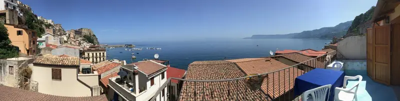 Vue panoramique sur un village côtier et la mer depuis une terrasse.
