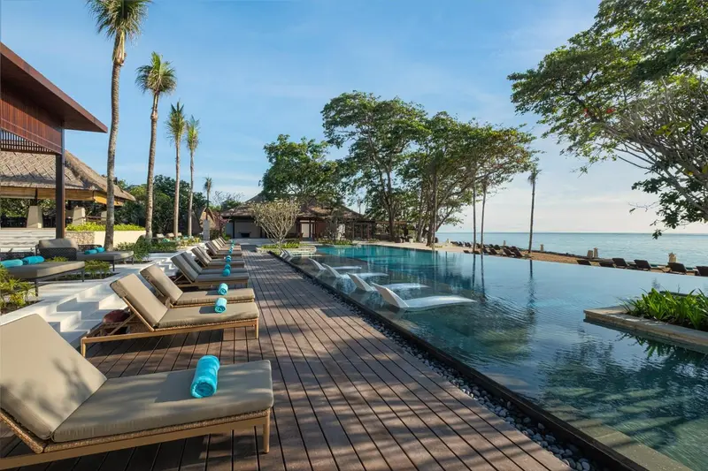 Transats alignés au bord d'une piscine à débordement avec vue sur la mer.