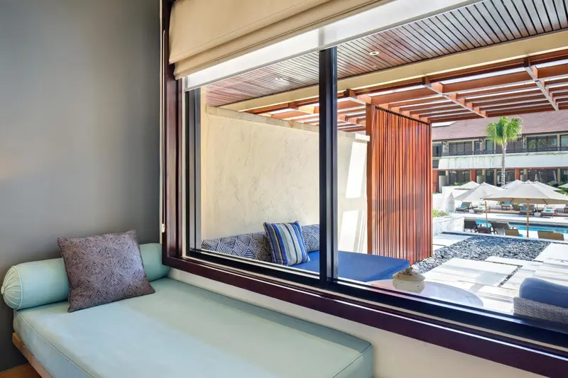 Espace de détente intérieur avec coussins et vue sur une piscine.