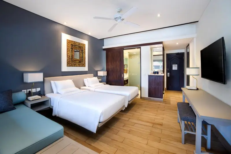 Une chambre lumineuse avec deux lits simples et un coin salon.