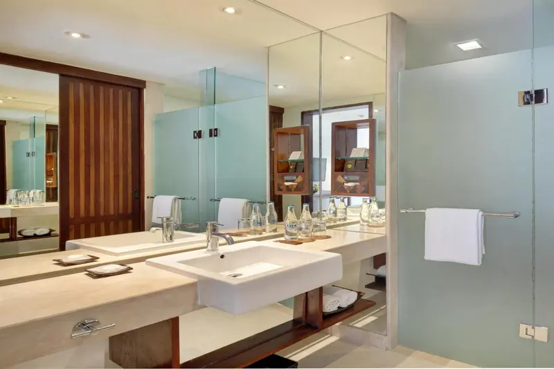 Une salle de bain lumineuse avec deux vasques et des miroirs.