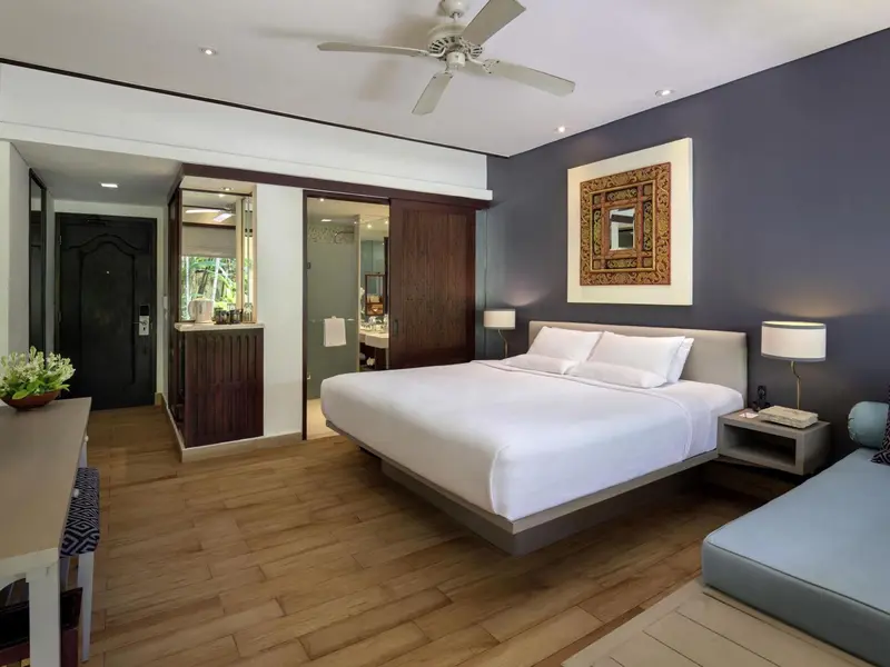 Une chambre lumineuse avec un grand lit et un coin salon.