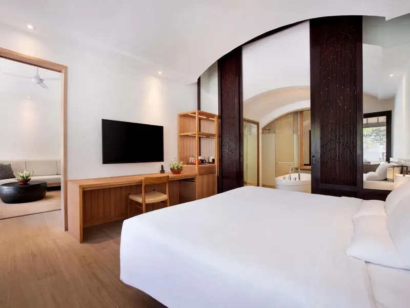Une chambre lumineuse avec un grand lit et un espace salon.