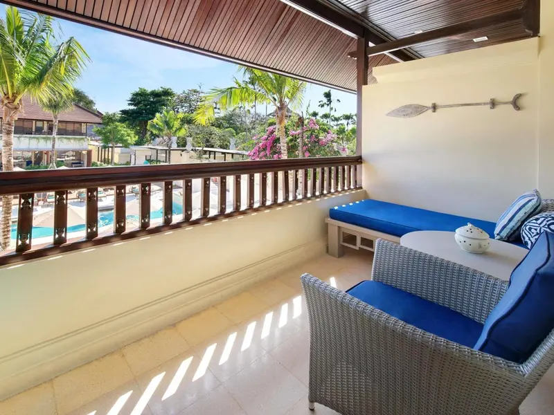 Terrasse aménagée avec salon et vue sur une piscine et la végétation.