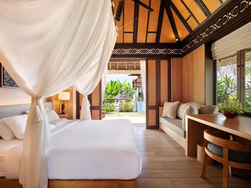 Une chambre lumineuse avec un lit à baldaquin donnant sur une végétation luxuriante.