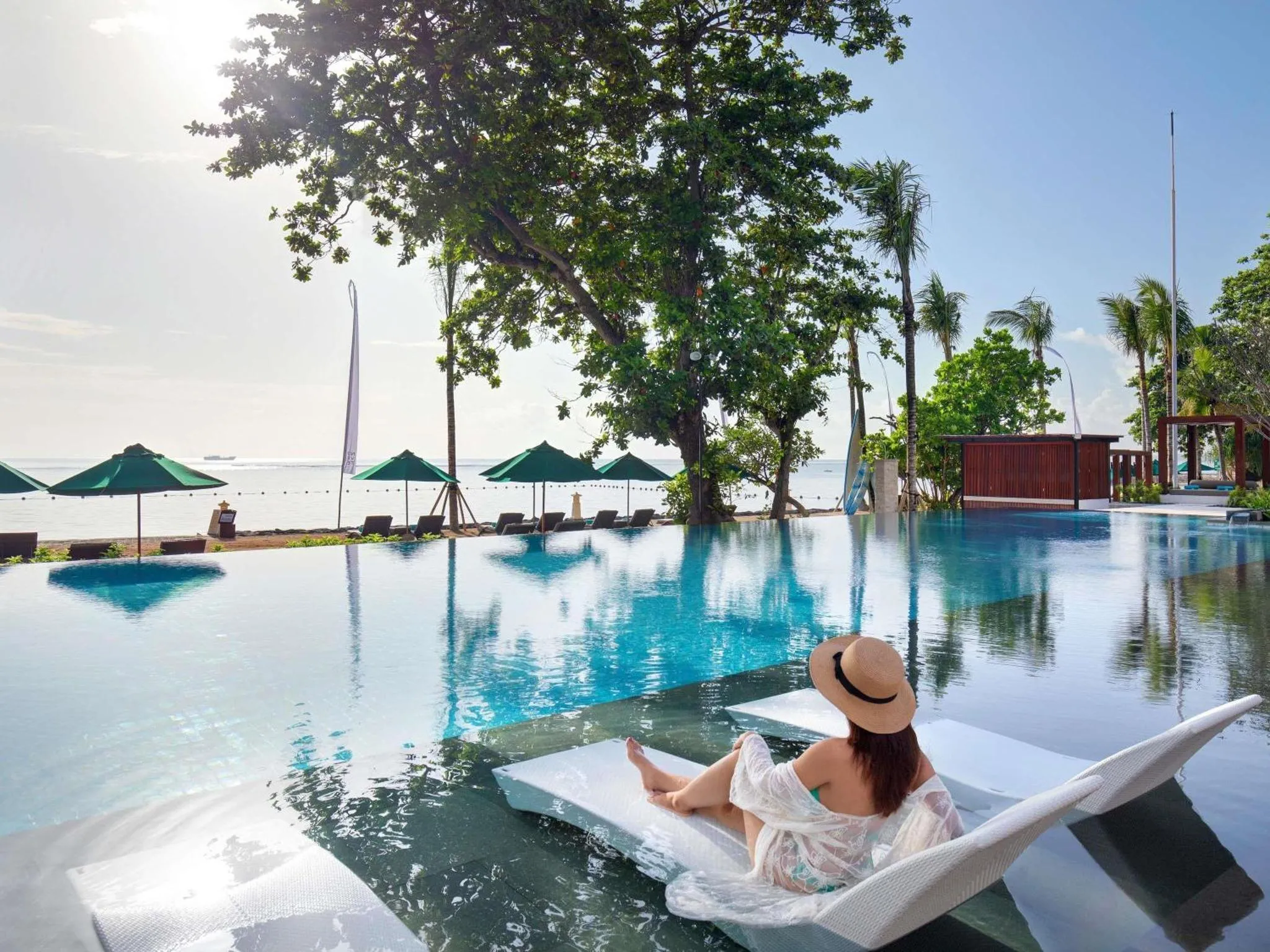 Une femme se relaxe au bord d'une piscine turquoise avec vue sur la mer.