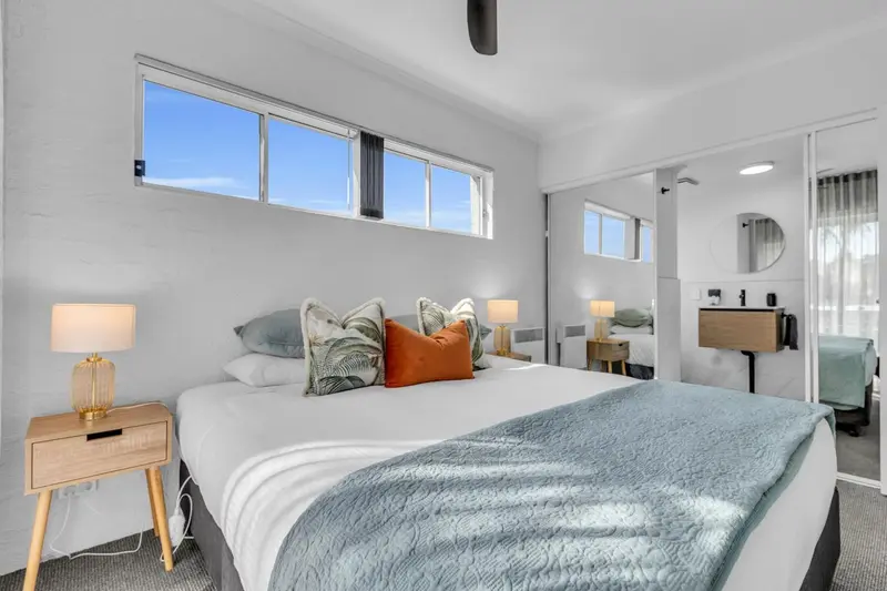 Une chambre lumineuse avec un grand lit et des oreillers décoratifs.