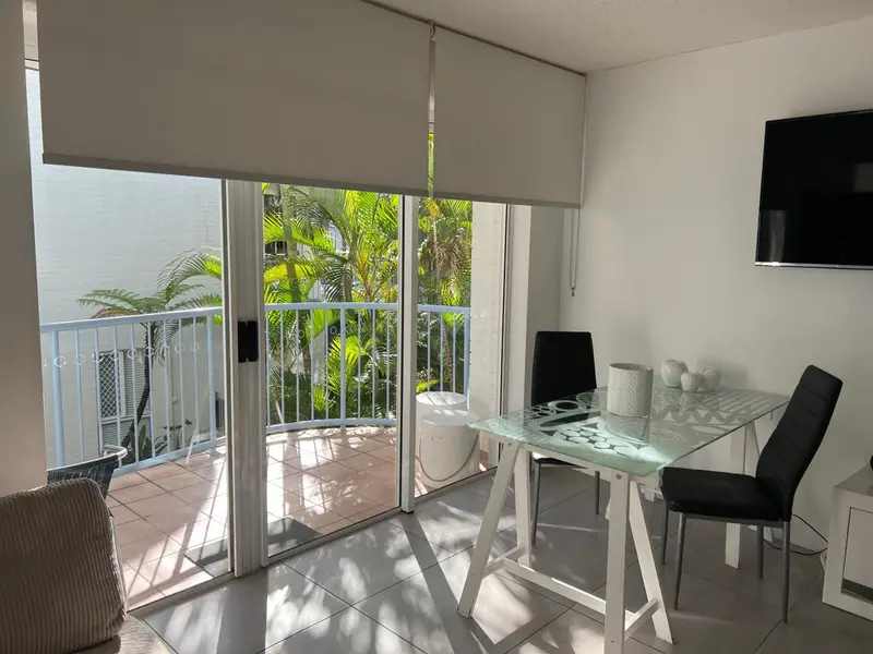 Une salle à manger lumineuse s'ouvre sur un balcon avec vue sur la végétation.
