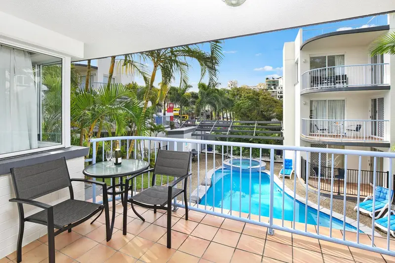 Terrasse avec mobilier de jardin donnant sur une piscine et une végétation tropicale.