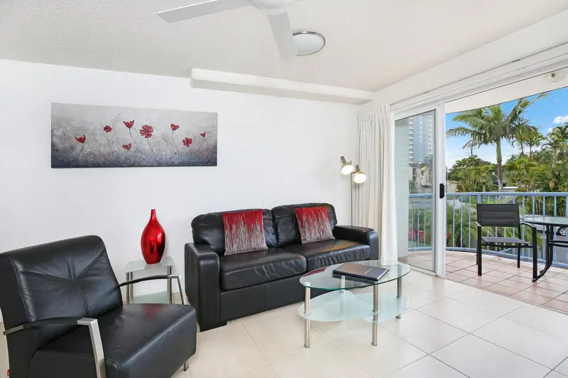 Un salon moderne s'ouvre sur un balcon avec vue sur la végétation.