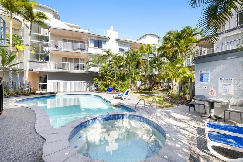 Piscine turquoise avec jacuzzi intégré dans un jardin tropical.
