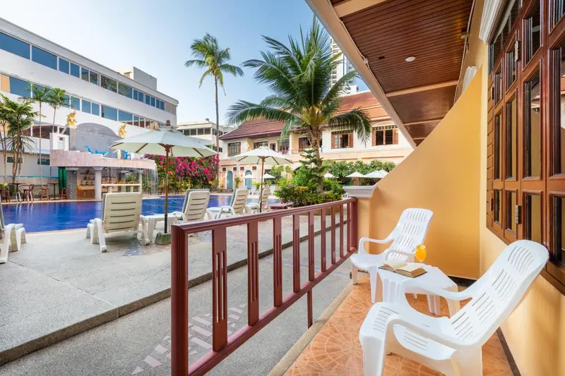 Terrasse avec mobilier d'extérieur donnant sur une piscine et un jardin tropical.