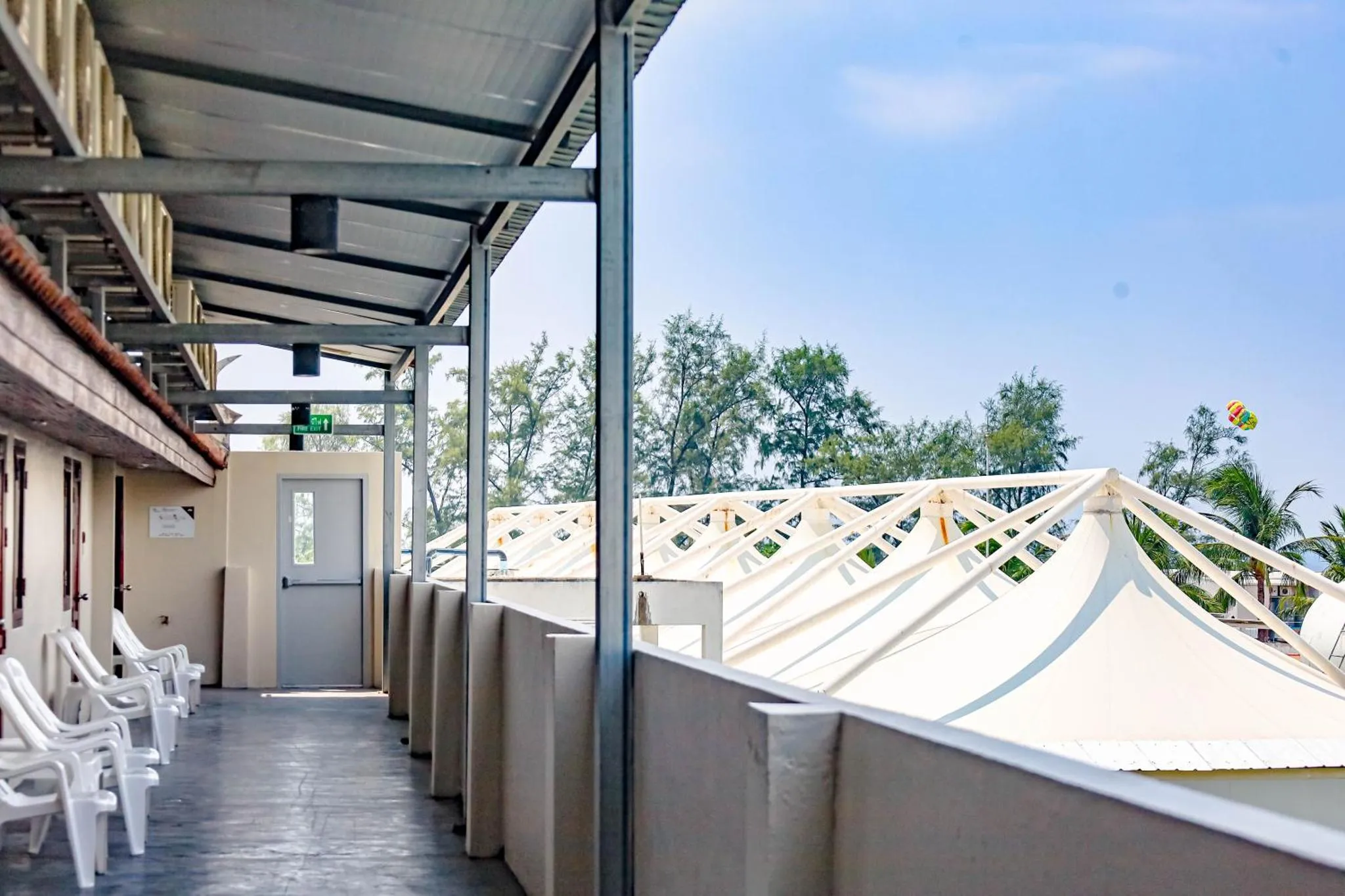 Terrasse ombragée avec des transats blancs et une vue sur la végétation.
