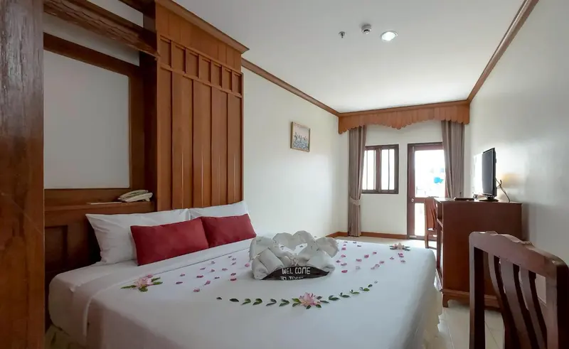 Une chambre d'hotel avec un lit decoré de fleurs et de serviettes.