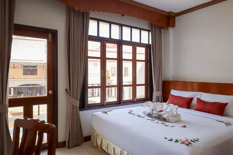 Une chambre lumineuse avec un lit décoré et une vue sur l'extérieur.