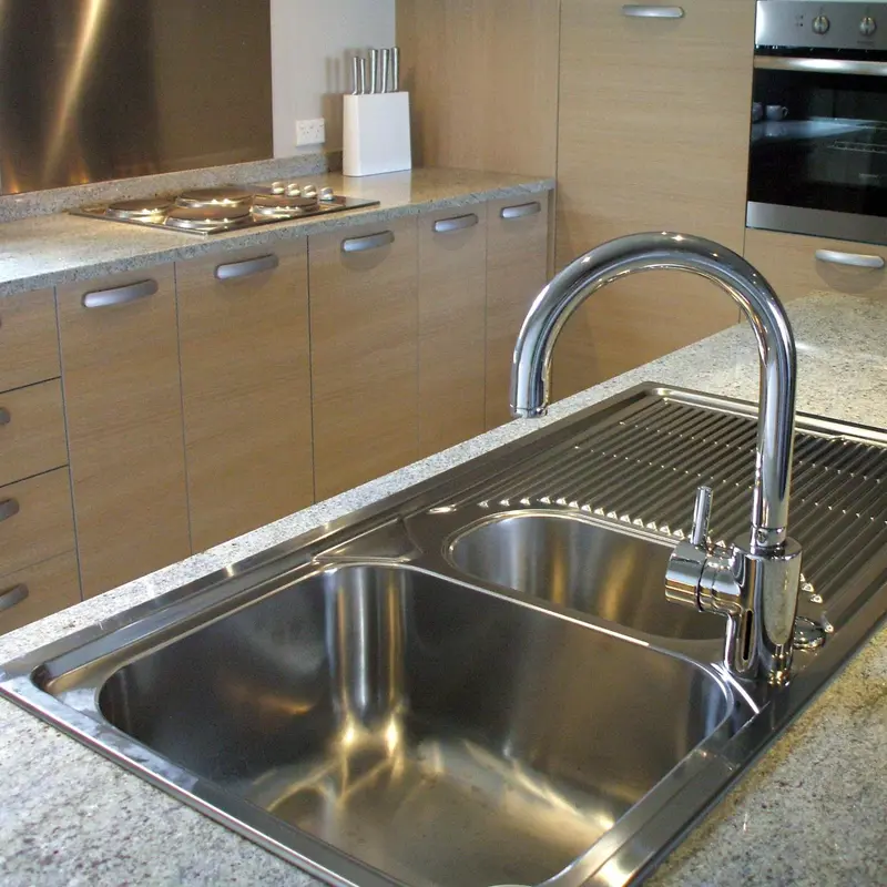 Cuisine moderne avec évier en inox et plaques de cuisson.
