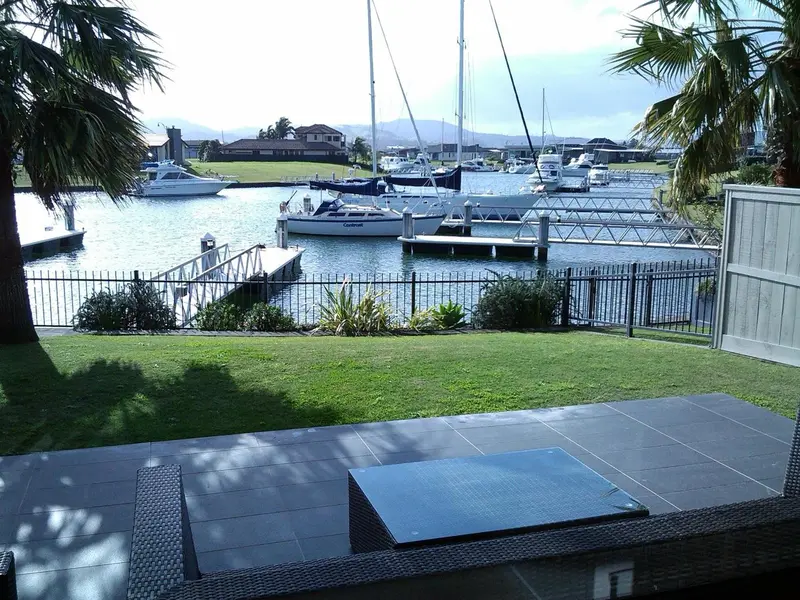 Terrasse carree avec mobilier de jardin donnant sur un port de plaisance.