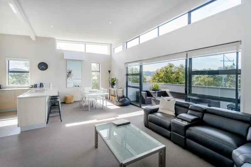 Espace de vie lumineux avec coin repas et canapé face à une grande baie vitrée.