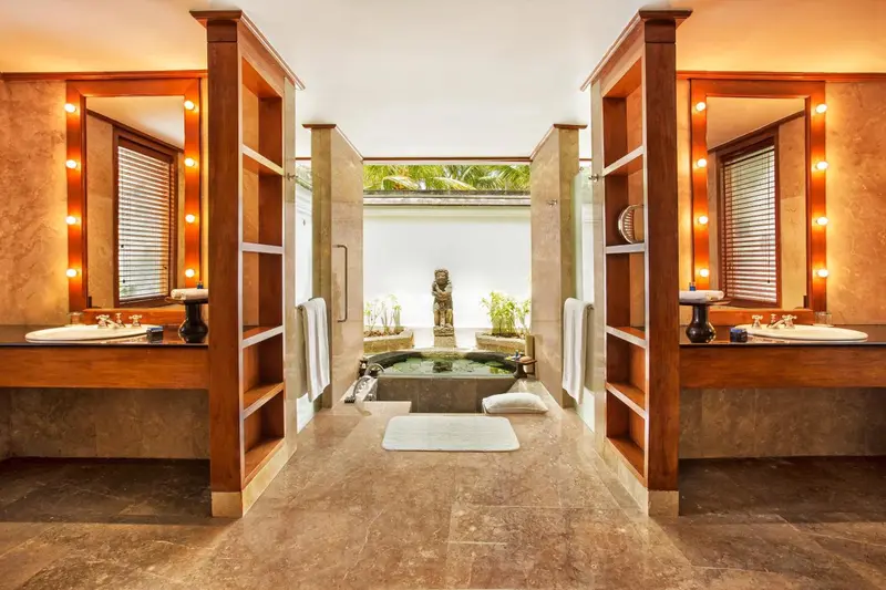 Deux vasques en bois et miroirs éclairés dans une salle de bain ouverte sur un bassin extérieur.