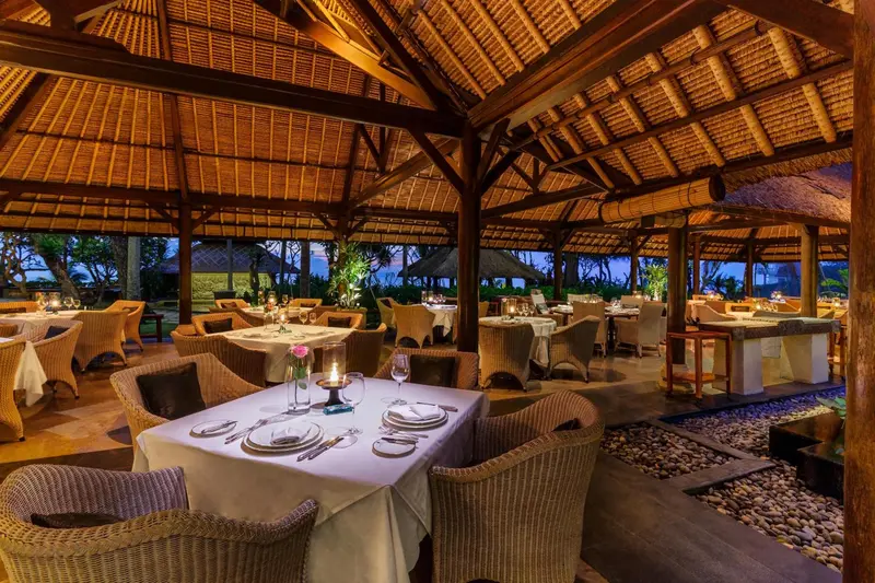 Une salle à manger extérieure avec des tables dressées pour le dîner.
