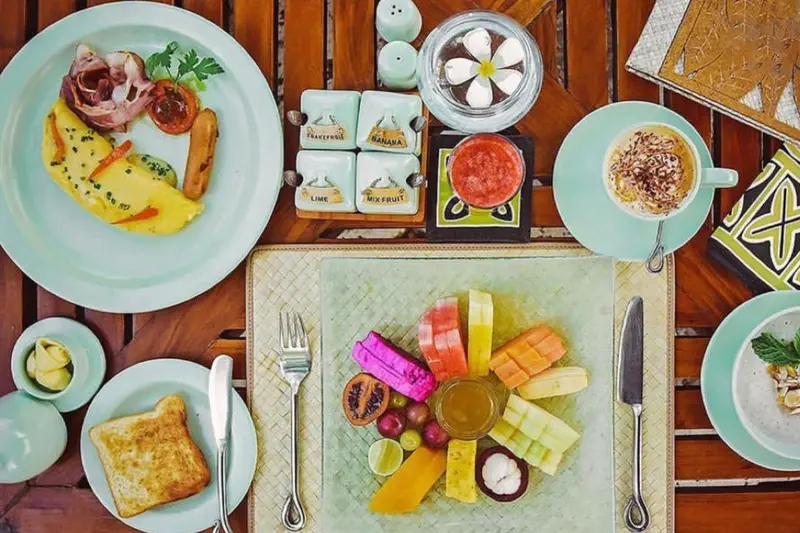 Table dressée avec des plats colorés de fruits et d'œufs.