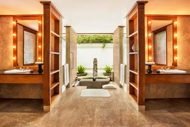 Salle de bain spacieuse avec deux vasques et une baignoire centrale.