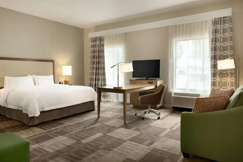 Une chambre lumineuse avec un grand lit et un espace bureau.