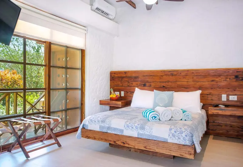 Une chambre lumineuse avec un grand lit et un accès à une terrasse.