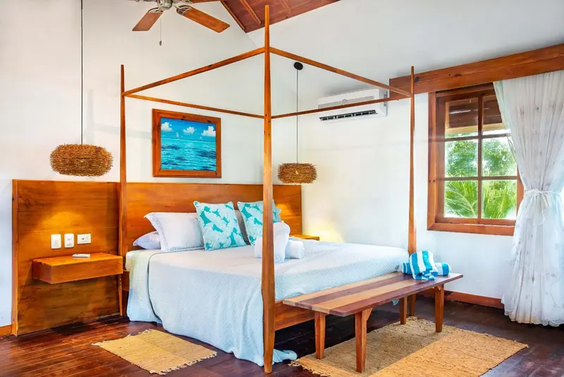 Une chambre lumineuse avec un grand lit à baldaquin en bois.