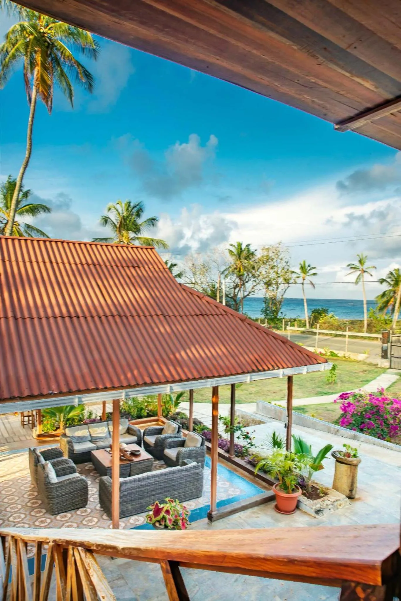 Terrasse ombragée avec mobilier de détente et vue sur la mer.
