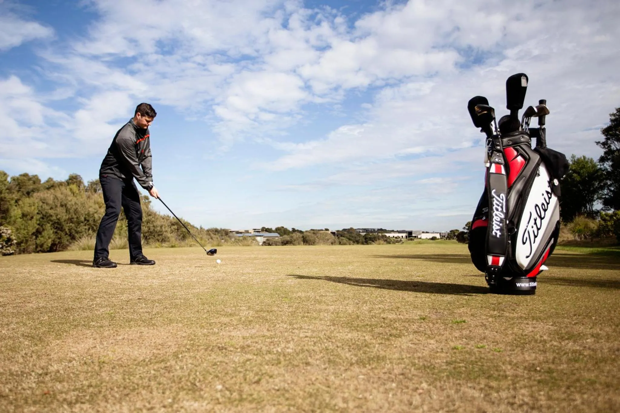 Un homme s'apprête à frapper une balle de golf sur un terrain verdoyant.