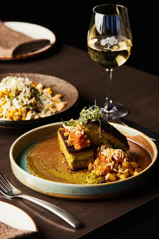 Une table est dressée avec des plats raffinés et une boisson.