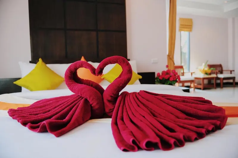 Un lit est decoré de serviettes en forme de cœur.