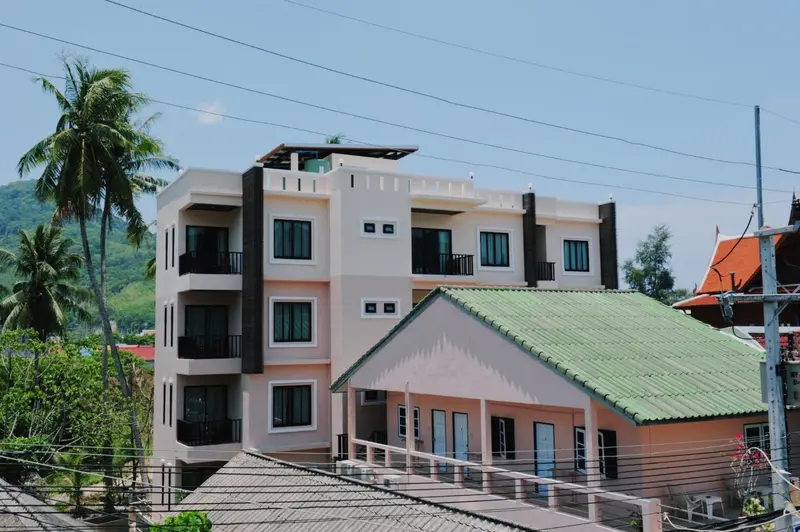 Bâtiment à étages avec des balcons et une toiture verte, entouré de végétation.
