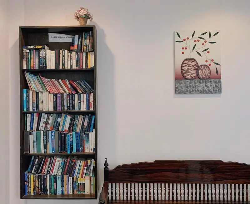 Bibliothèque remplie de livres et décoration murale dans une pièce lumineuse.