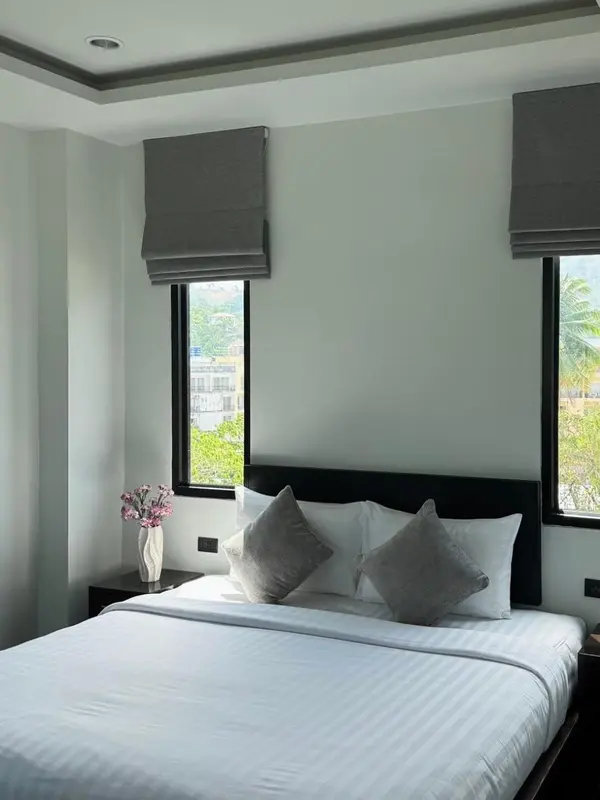 Une chambre avec un lit double et deux fenêtres.