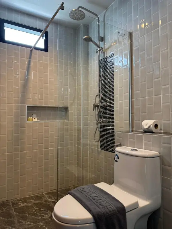 Une douche à l'italienne moderne avec des carreaux gris et des accessoires chromés.