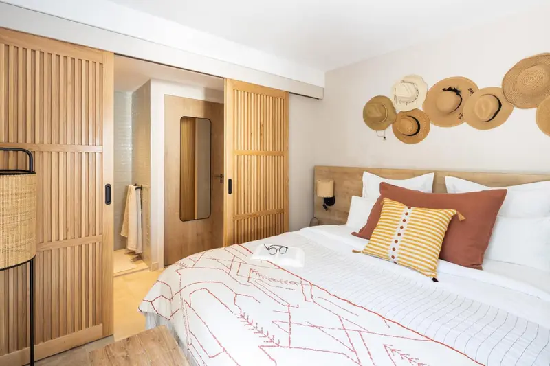 Une chambre lumineuse avec un grand lit recouvert d'une courtepointe décorative et des chapeaux accrochés au mur.