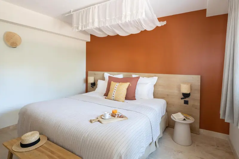Une chambre lumineuse avec un lit recouvert d'une moustiquaire et décoré de coussins.