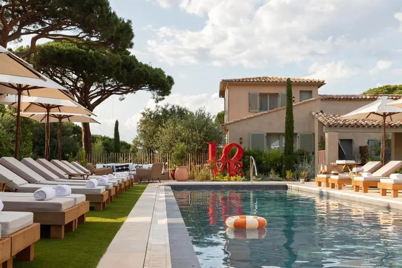 Transats alignés au bord d'une piscine rectangulaire dans un jardin verdoyant.