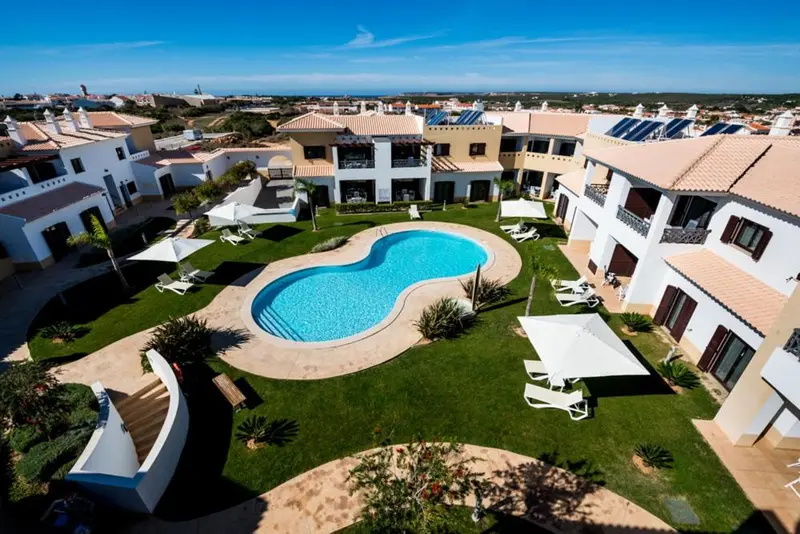 Vue aérienne d'un complexe hôtelier avec piscine et pelouse verdoyante.