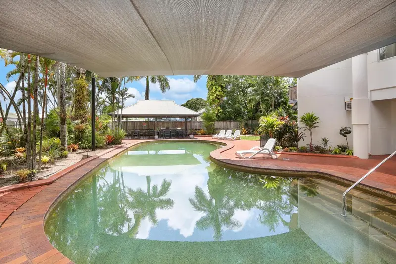 Piscine rectangulaire entourée d'une terrasse carrelée et de végétation tropicale.