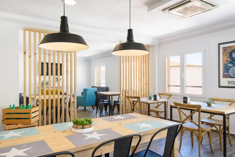 Une salle lumineuse avec des tables et des chaises en bois.